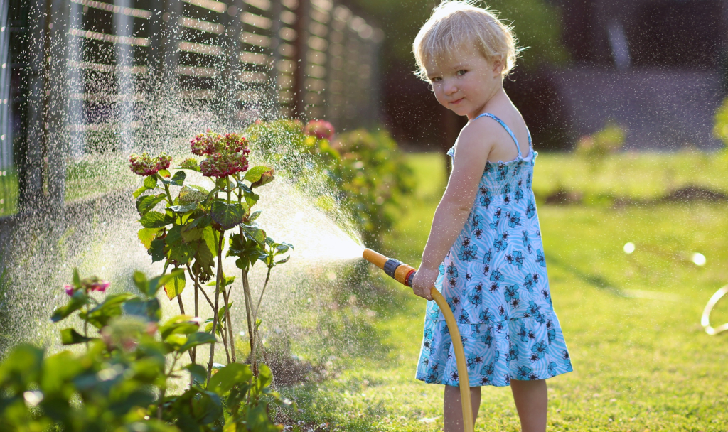 Little,Child,,Adorable,Blonde,Toddler,Girl,,Watering,The,Plants,,Beautiful bimba annaffia ortensie in estate